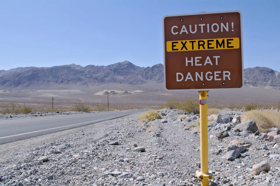 'Caution Extreme Heat Danger' sign in Death Valley, California with desert mountains in background